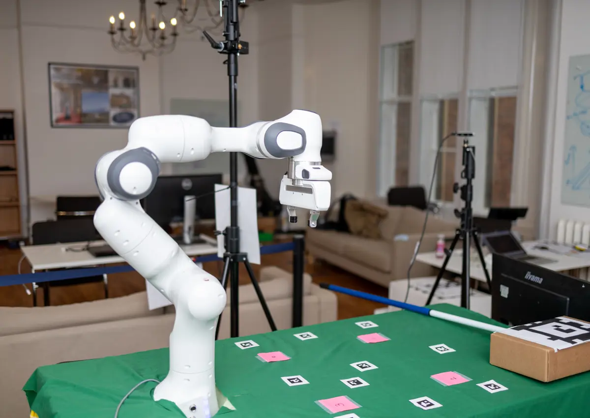 Panda robot arm on green table with cards.